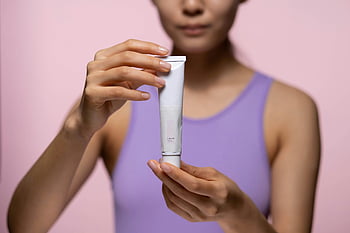 wanita, Tank top ungu, Krim perawatan kulit, krim tangan, latar belakang merah muda, Pengaturan Studio, produk kecantikan, perawatan kulit, keindahan, wanita memegang krim, perawatan kulit rutin