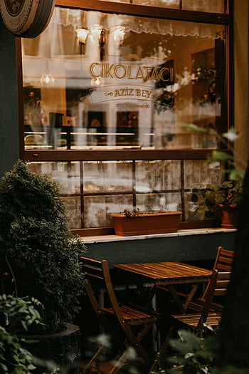 udendørs cafe, træmøbler, frodige planter, Varm atmosfære, Inviterende indstilling, café vindue, Charmerende omgivelser, bord og stole, udendørs siddepladser, Hyggelig atmosfære, Cafe Indretning