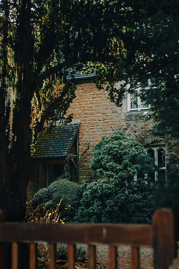 green trees, brown brick building, rustic brick cottage, lush greenery, tranquil scene, natural setting, outdoor scenery, peaceful environment, countryside home, architectural charm, serene landscape