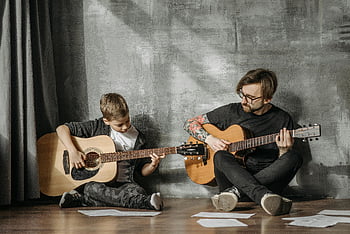 uomo e bambino che giocano chitarre, Scena commovente, Chitarra insegnante, impostazione interna, chitarre acustiche, ragazzo che impara la chitarra, Lezione di musica, padre e figlio, legame musicale, attività di famiglia, Pratica della chitarra