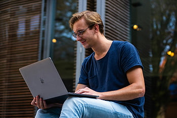 ember használ laptop, szelektív összpontosít, kültéri beállítás, fiatal férfi, Leiden Hollandia, dolgozik laptop, alkalmi viselet, kék ing, Farmer, természetes fény, nyugodt testtartás