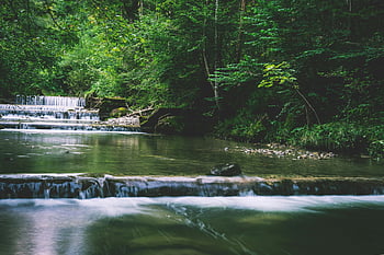 flowing multi-tier waterfalls, serene forest stream, cascading waterfalls, lush green trees, peaceful nature scene, forest waterfalls, natural landscape, greenery, tranquil scene, outdoor scenery, waterfall cascade