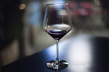 wine glass, red wine, clear glass, dark table, indoor setting, close-up, glassware, beverage, stemware, drinking glass, alcohol
