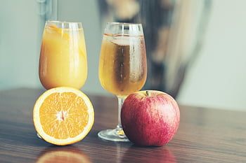 apple cider, orange juice, fresh apple, orange slices, clear wine glasses, refreshing display, fruit drinks, apple slices, orange juice glass, apple cider glass, fruit beverages