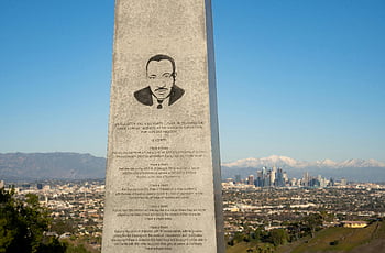 Martin Luther King Jr., monument, Los Angeles skyline, mountain backdrop, gray concrete, blue sky, civil rights, historical site, urban landscape, outdoor memorial, scenic view