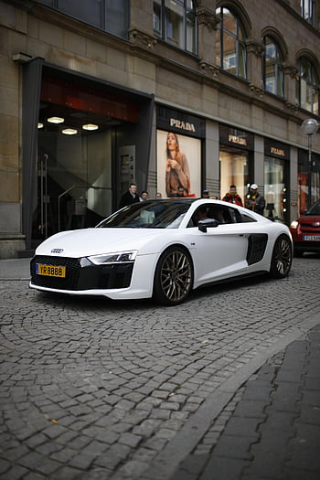 white luxury car, white Audi R8, parked on street, cobblestone street, retail stores, Prada store, urban setting, sports car, white sports car, city street, luxury vehicle