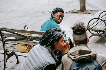 unrecognizable friends, gossiping, street, young adults, conversing, park bench, sharing secrets, building trust, outdoor setting, casual interaction, social connection