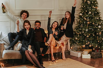friends having a party, joyful group, adults celebrating, champagne, laughter, indoors, decorated Christmas tree, holiday celebration, festive gathering, New Year's party, Christmas party