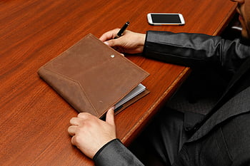 mandlig direktør, Skrivning af noter, forretningsmøde, læder notesbog, Brun læderbog, skrivebord, pen, smartphone, Professionel omgivelse, Kontormiljø, formel påklædning