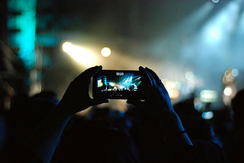 grabación de conciertos, persona grabando, grabación de vídeo, grabación de teléfonos inteligentes, escenario de concierto, luces de escenario, actuación en vivo, grabación de audiencia, Ambiente de concierto, evento musical, música en vivo