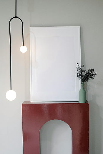 modern room, empty frame, blank framed artwork, elegant hanging lamp, decorative vase, red mantle, interior design, minimalist decor, contemporary style, home decor, modern furniture