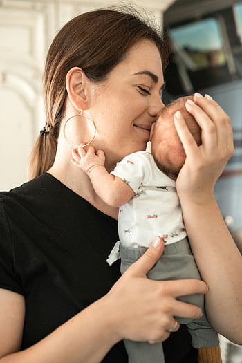 Madre besando bebé, momento tierno, Amarto, bebé recién nacido, foto de interior, maternidad, vínculo familiar, Conexión emocional, madre e hijo, cuidado del bebé, madre cariñosa