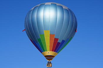 hot air balloon, blue sky, vibrant colors, floating balloon, clear sky, sense of freedom, aerial view, colorful balloon, outdoor activity, sky adventure, hot air ballooning