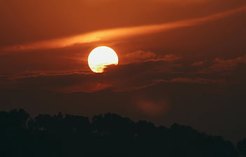 solnedgång, silhuett träd, varma färger, dramatisk himmel, apelsinhimmel, kvällsljus, naturligt landskap, solnedgång fotografering, himmelfärger, träd silhuetter, solnedgång scen