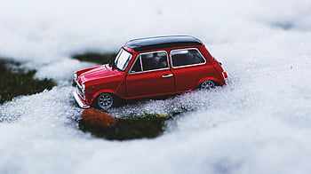 vintage car, snow, red toy, Mini Cooper, close-up, wintertime, playfulness, toy car, snowy scene, outdoor play, miniature vehicle