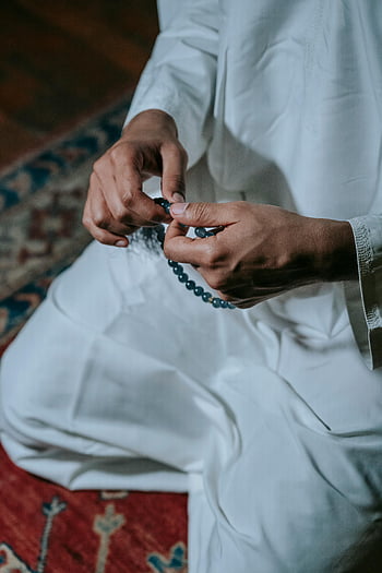 man praying, prayer beads, traditional attire, faith, spirituality, hands, beads, white robe, religious practice, prayer, meditation
