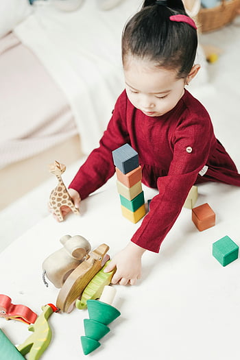 Mädchen im roten Kleid, Holzblöcke, Buntes Holzspielzeug, Junges Mädchen spielt, Spielzeit zu Hause, Indoor-Spiel, Kinderspielzeug, Bildungsspielzeug, Kleinkindaktivitäten, Heimspiel, Holzspielzeug