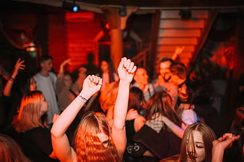 Natfest, folk danser, hænder hævet, Levende scene, livlig natklub, Klubatmosfære, natteliv, Social sammenkomst, energisk skare, feste, Nattelivsunderholdning