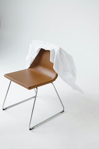 white shirt, draped shirt, brown chair, studio environment, minimalist design, white background, modern chair, white fabric, draped fabric, studio photography, minimalist photography