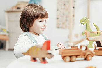 fiú, Fehér hosszú ujjú teteje, játszik, játék, fa dinoszaurusz játékok, fényes játszószoba, boldog gyermek, fából készült játékok, játszószoba beállítás, dinoszaurusz játékok, gyermek játszik