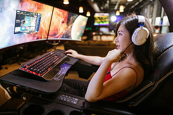 女性のゲーム、 デュアルモニター、 白いヘッドフォン、 モダンなセットアップ、 レッドトップ、 若い女性、 テレビゲーム、 ゲーム設定、 コンピューターゲーム、 ゲーミングチェア、 キーボードとマウス