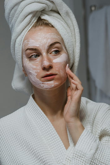 krim wajah, perawatan kulit rutin, wanita mengoleskan krim, mantel mandi, handuk di kepala, perawatan wajah, perawatan kulit, rutinitas kecantikan, perawatan diri, masker wajah, produk perawatan kulit