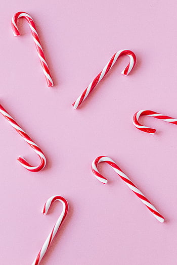 candy canes, red and white, pastel pink, holiday themes, striped candy, Christmas candy, festive background, candy cane arrangement, pink surface, holiday decoration, candy cane design