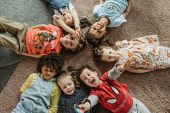 children lying on carpet, happy children, diverse children, carpet playtime, group of children, enjoying playtime, children together, diverse group, carpet fun, kids playing, children smiling