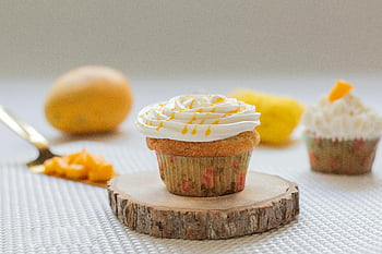 mango cupcake, cream frosting, fresh mango pieces, close-up, sweet cupcake, dessert, bakery, food photography, cupcake decoration, fruit topping, white frosting