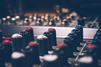 audio mixer, macro shot, audio equalizer, dimly lit studio, music themes, technology themes, close-up knobs, studio equipment, sound mixing, audio production, music technology