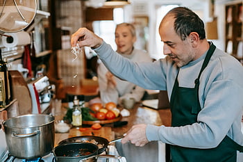 couple cooking, homemade cuisine, fresh ingredients, kitchen, man preparing food, stove, lunch, apron, vegetables, cooking together, homemade meal
