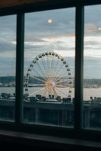 Seattle Ferris Wheel, twilight view, illuminated Ferris Wheel, body of water, scenic view, through window, Seattle waterfront, evening scenery, urban skyline, waterfront attraction, twilight Ferris Wheel
