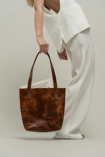 woman, brown leather bag, stylish woman, minimalist studio, white outfit, tote bag, fashion photography, modern style, studio setting, handbag, accessories