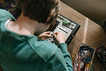 computer hardware repair, young person, hands-on technology, green sweater, technology skills, computer repair, electronics repair, computer components, technology education, tech skills, computer maintenance