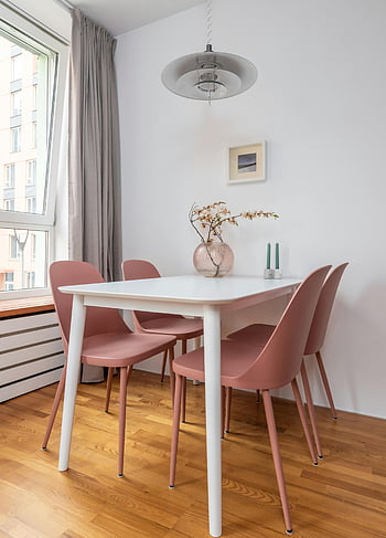 interni semplici, Comoda sala da pranzo, tavolo e sedie, luminoso minimalista, sedie rosa, arredamento elegante, tavolo bianco, pavimento di legno, area da pranzo moderna, luce sospesa, opere d'arte incorniciate