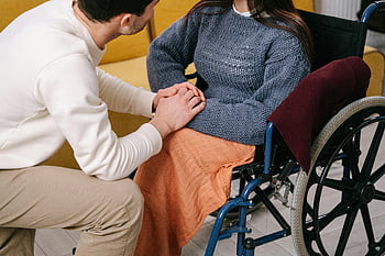 手を握っている男、 車椅子の女性、 ケアとサポート、 屋内設定、 車椅子ケア、 協力的なジェスチャー、 身体的支援、 心の支え、 車椅子ユーザー、 介護者の相互作用、 屋内ケアシーン
