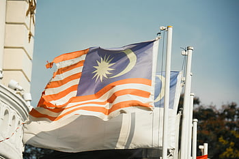 Malaysian flag, clear blue sky, national pride, patriotism, vibrant flag, waving flag, assorted flags, outdoor scene, flagpole, blue sky, national symbol