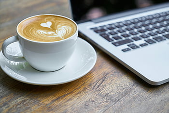 káva, latte, šálek kávy, podšálek, laptop, dřevěný stůl, Útulné nastavení práce, latte art, srdce design, kávový šálek, pracovní stůl
