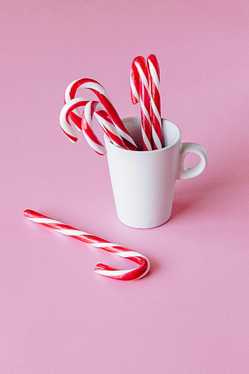 candy canes, white ceramic mug, red and white candy canes, holiday themes, pink background, vibrant candy canes, white cup, festive, Christmas, candy cane mug, holiday decor