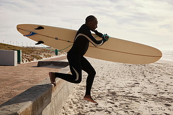 Schwarzer Surfer, zum Meer rennen, Surfbrett, tagsüber, Neoprenanzug, auf den Strand springen, Dynamischer Schuss, Mann, Strand, Ozean, Surfen
