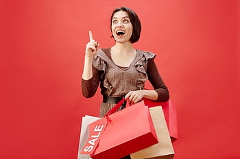 woman, brown dress, shopping bags, cheerful, sale, vibrant red backdrop, celebrating, fashion, retail, consumerism, lifestyle