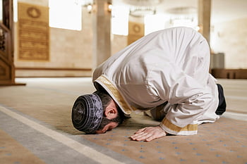 Muslim man, white thobe, bowing down, praying, mosque, traditional attire, cultural reverence, Islamic prayer, religious practice, mosque interior, prayer position