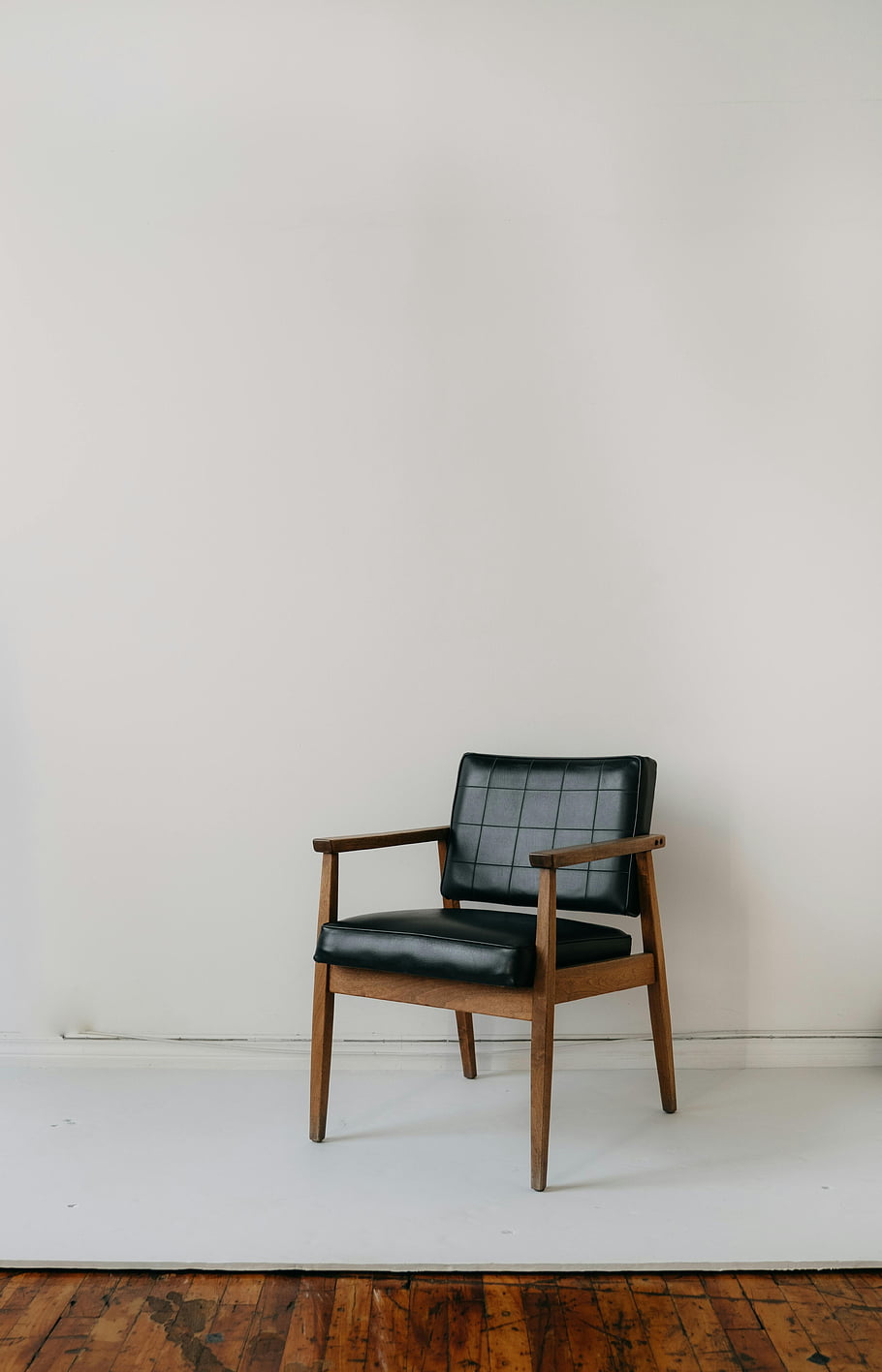 Retro křeslo, kožené křeslo, Vintage křeslo, minimalistické nastavení, vnitřní nábytek, prosté zdi, Dřevěné loketní opěrky, Černá kůže, moderní století, Jednoduchý výzdoba, vnitřní židle