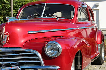 red vintage car, classic automotive design, shiny red car, chrome details, parked near tree, vintage vehicle, classic car, red car, chrome car, vintage automotive, classic red vehicle