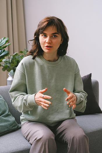 woman, sofa, therapy office, sharing problems, comfortable setting, gesturing, seated, expressing conversation, indoor, casual attire, plant