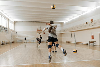 people playing volleyball, indoor sports hall, dynamic volleyball match, active players, volleyball game, indoor volleyball, sports activity, volleyball players, sports hall, volleyball action, indoor court