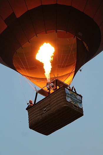 hot air balloon, bright burning fire, cloudless sky, clear twilight sky, adventure, aircraft balloon, ignited fire, flying balloon, photo caption, photo description, SEO keywords