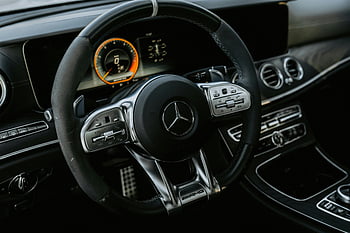 Mercedes steering wheel, luxury car interior, dashboard controls, close-up view, Mercedes car, interior design, steering wheel controls, dashboard display, car interior, Mercedes logo, AMG steering wheel