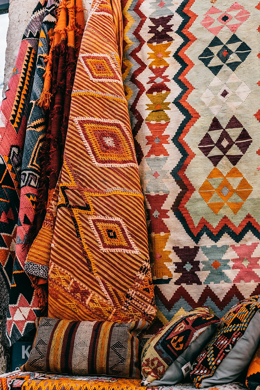 colorful carpets, oriental rugs, Cappadocia market, Turkish textiles, decorative cushions, wall display, vibrant patterns, traditional crafts, cultural market, handmade rugs, ethnic decor