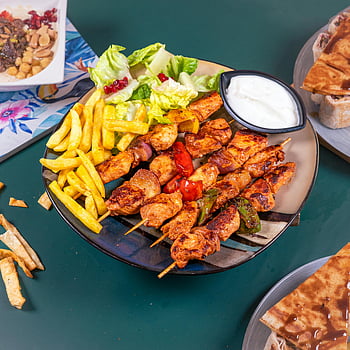 roasted chicken, fries, salad, grilled chicken skewers, dipping sauce, savory meal, chicken kebabs, side salad, french fries, meal presentation, food photography
